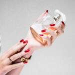 person holding clear glass bottle of luxury perfume