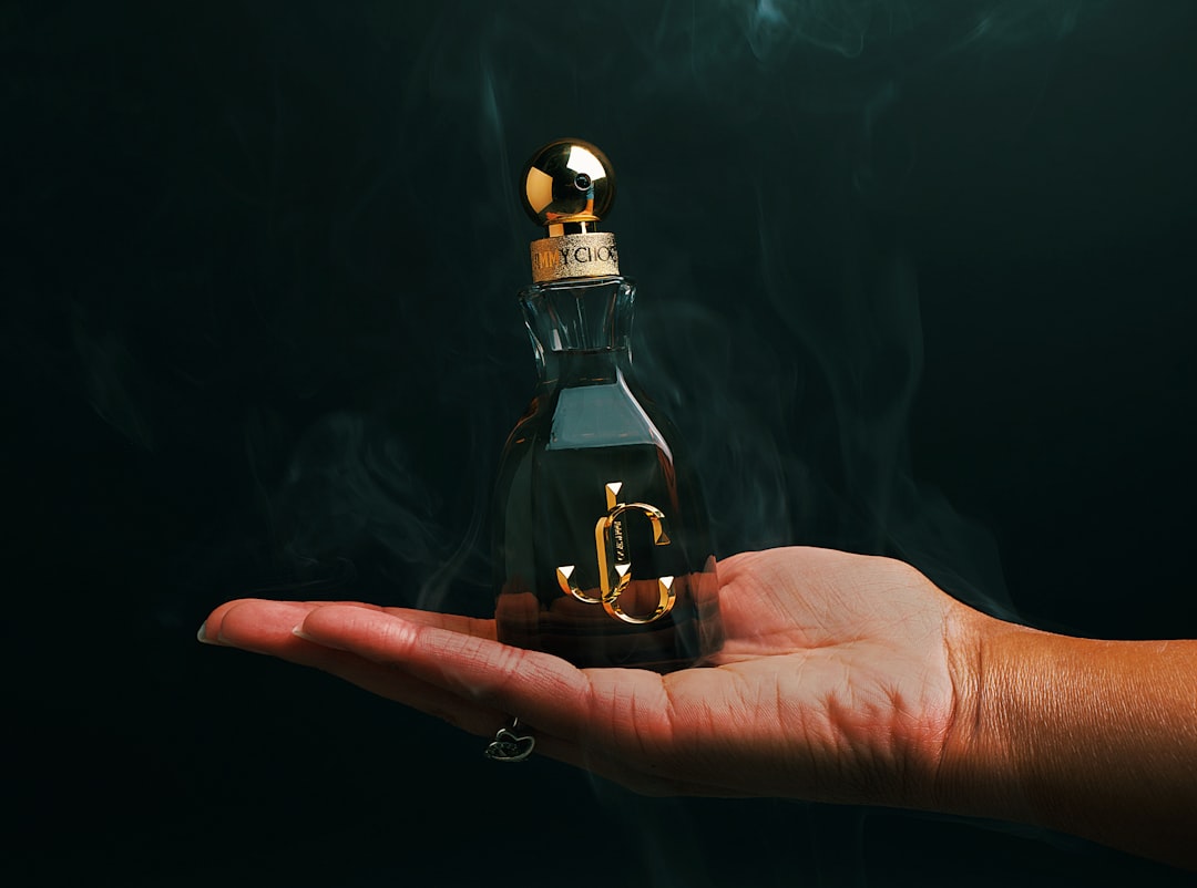 Hand holding up the Jimmy Choo's A person holding a small bottle with an anchor on it